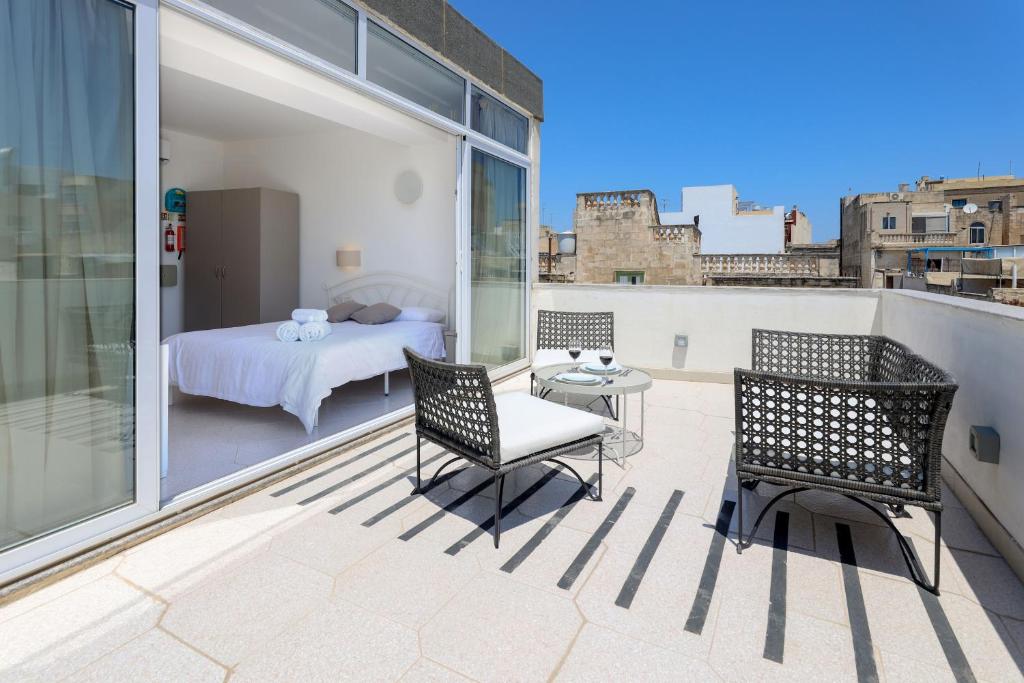 a balcony with a bed and two chairs and a table at Ta Gianni Guest House in Sliema