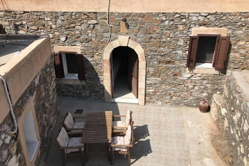 a patio with chairs and a stone building with a doorway at Yiannis Village house in Asklipiḯon