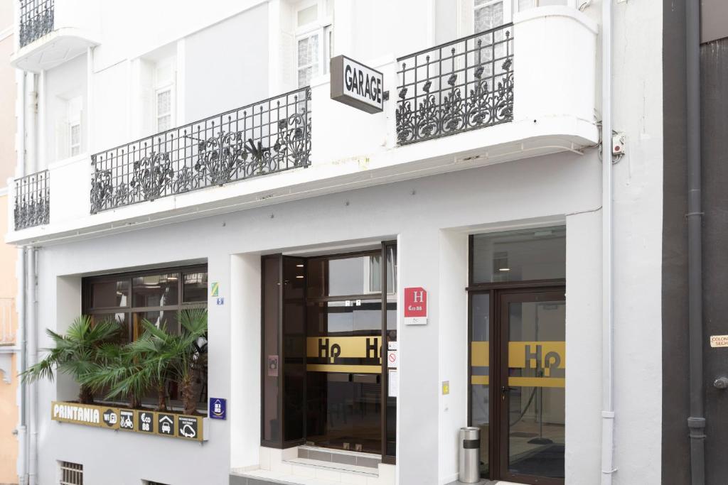 a white building with two balconies on top of it at Hotel Printania in Lourdes