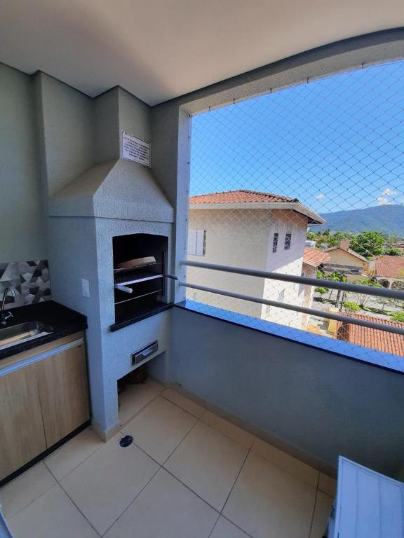 a kitchen with a balcony with a pizza oven at Apto no Itaguá - Varanda Gourmet e Lazer completo in Ubatuba