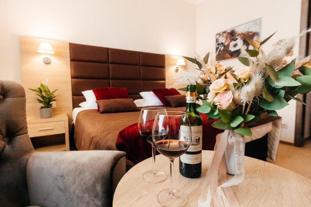 a hotel room with a table with two glasses of wine and flowers at Hotel "VITAMIN" in Krasnodar