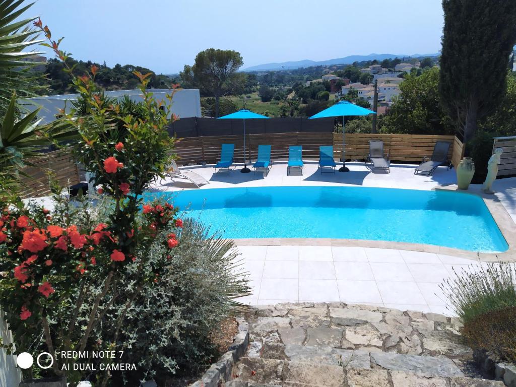 una piscina en un patio con sillas y flores en VILLAS-Piscine les MIMOSAS, en Fréjus