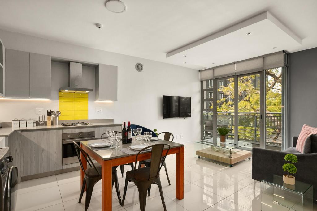 Una cocina con una mesa y sillas en una habitación. en Easy Stay - The Median Rosebank, en Johannesburgo