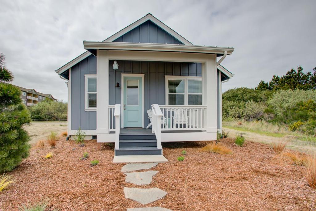 a small blue house with a porch and a chair at Sand Castle Cottage - Oyhut Bay Seaside Village in Ocean Shores