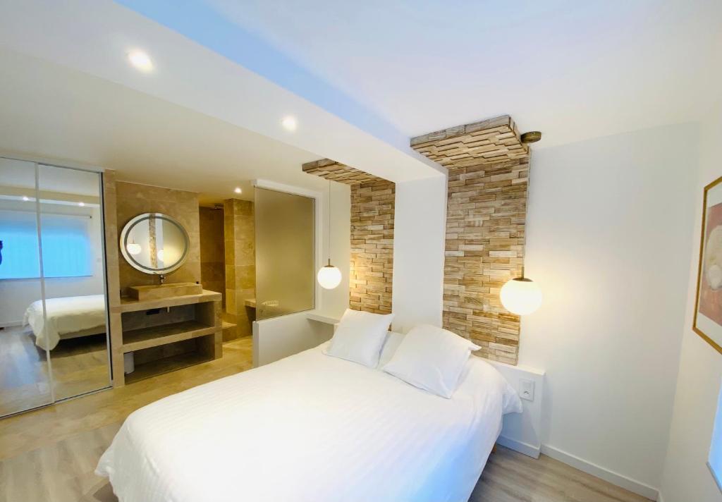 a bedroom with a white bed and a mirror at Feel@Home Nemausus « Le 21 » in Nîmes
