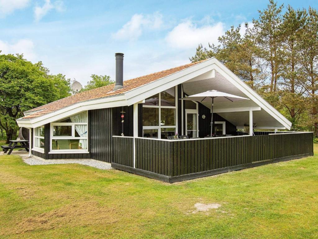 een huis met een grote afgeschermde veranda met een paraplu bij 6 person holiday home in Jerup in Jerup