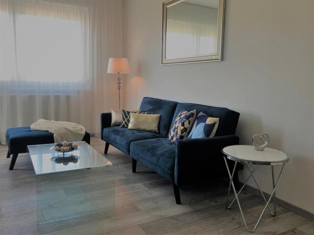 een woonkamer met een blauwe bank en een tafel bij Glamour Apartman in Tapolca