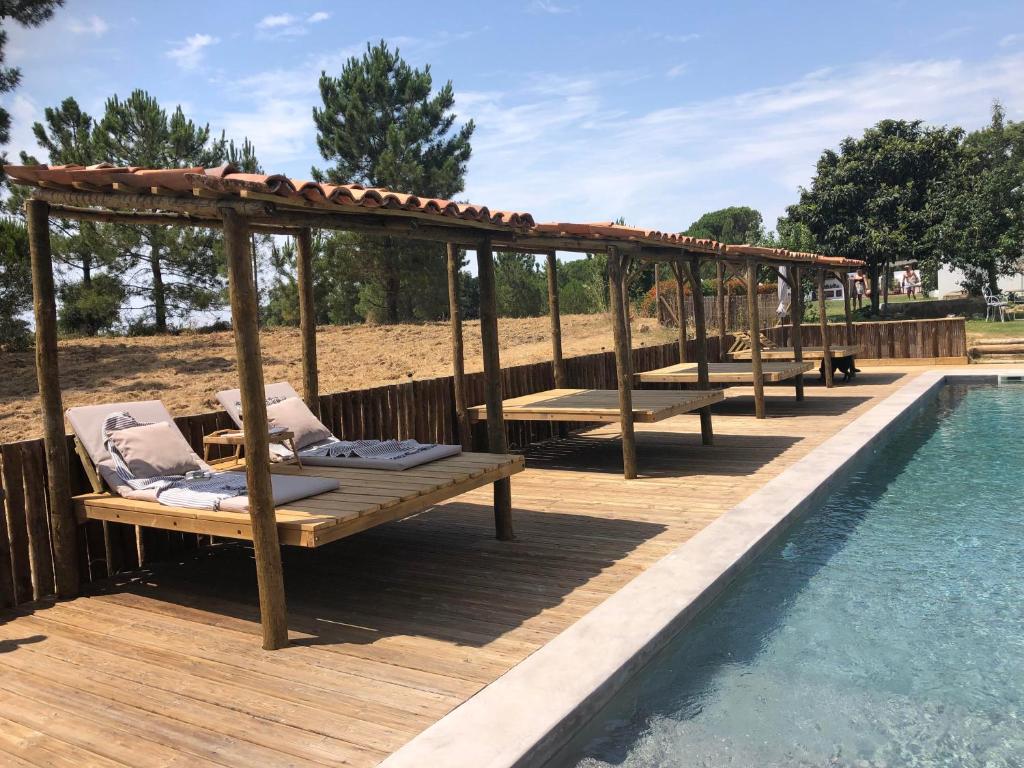 una terraza de madera con bancos junto a una piscina en Ponte Pedra - Melides Country House Adults Only, en Melides