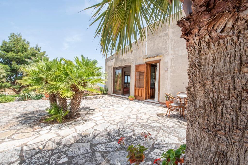 a patio with a palm tree and a house at Baglio Cracchiolo, "Casa Maria" in San Vito lo Capo