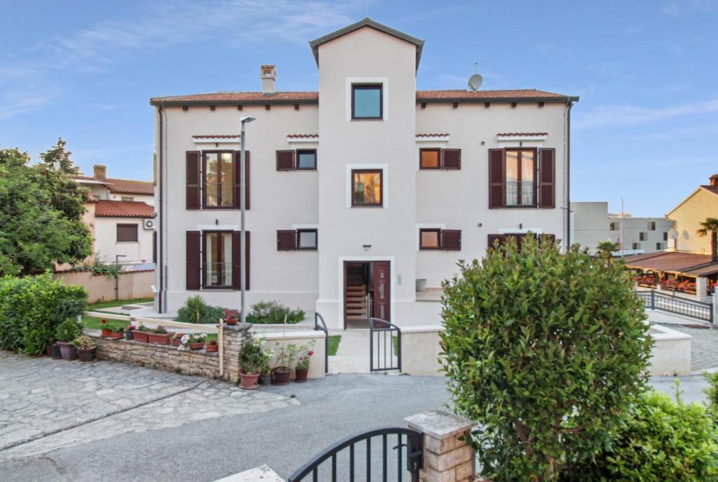 a large white house with a courtyard at Apartments Villa Alba in Poreč