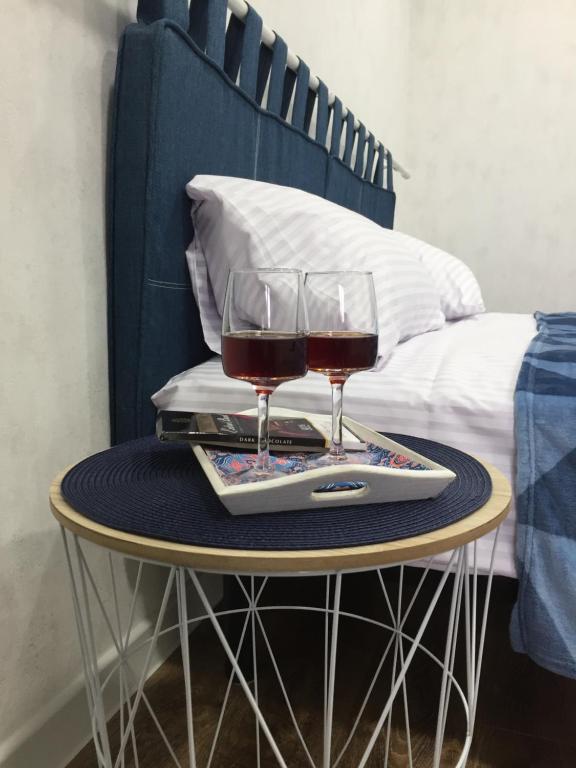 dois copos de vinho numa mesa ao lado de uma cama em Toledo Apartments em Kharkov