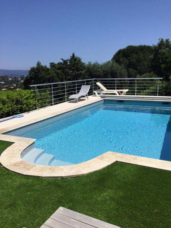a swimming pool with a chair and some grass at La vigie in Cavalaire-sur-Mer