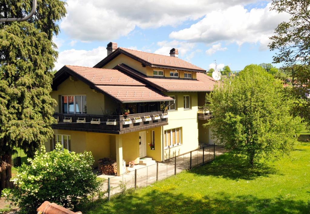 une grande maison jaune avec un toit rouge dans l'établissement Garden's apartman - Kosjerić, à Kosjeric
