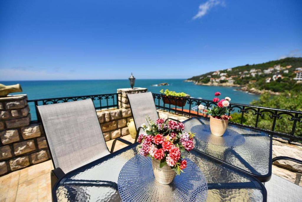 a table with two chairs and flowers on a balcony at Apartments Antigona Old Town in Ulcinj