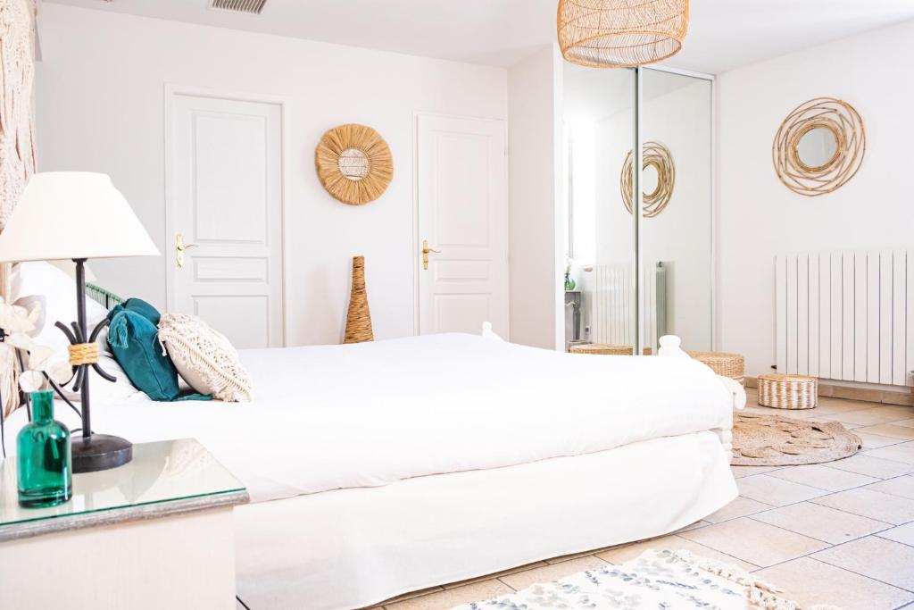 Dormitorio blanco con cama blanca y espejo en Logis hôtel et restaurant La Bastide Cabezac en Bize-Minervois