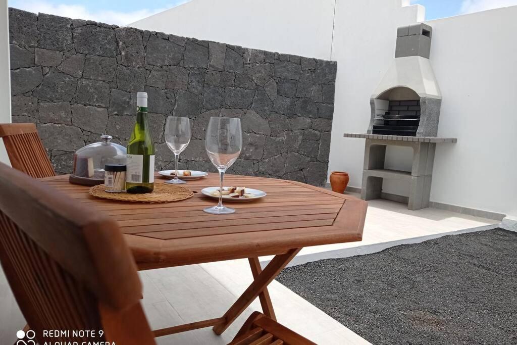 a wooden table with two wine glasses and a fireplace at Precioso apartamento con terraza en Teguise in Teguise