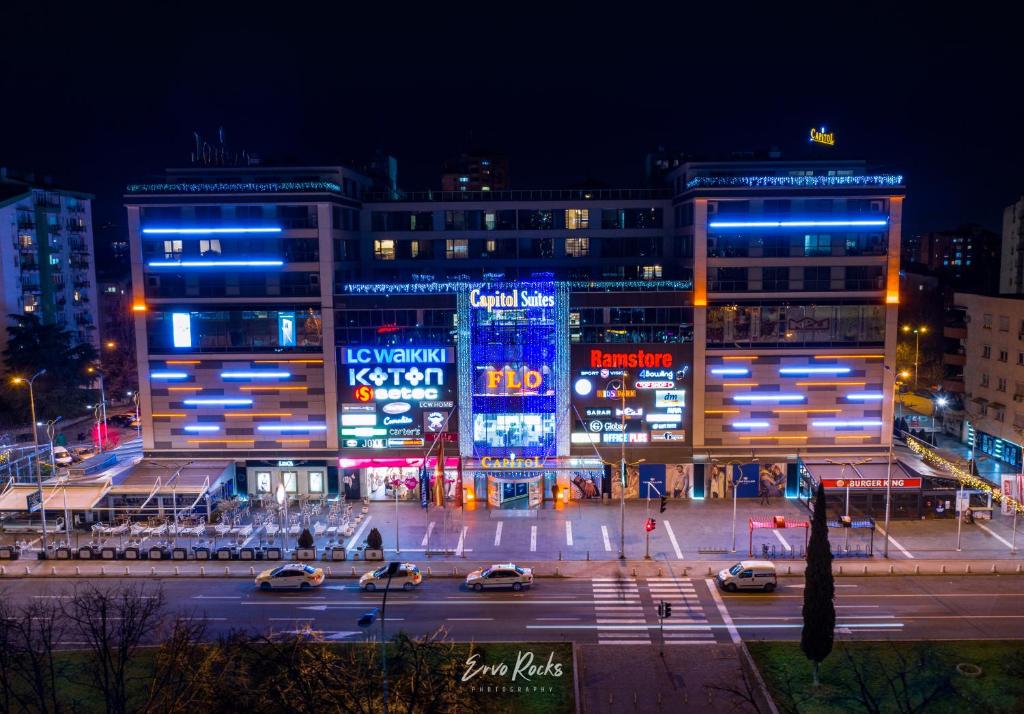 uma cidade iluminada à noite com carros numa rua em Capitоl Suites em Skopje