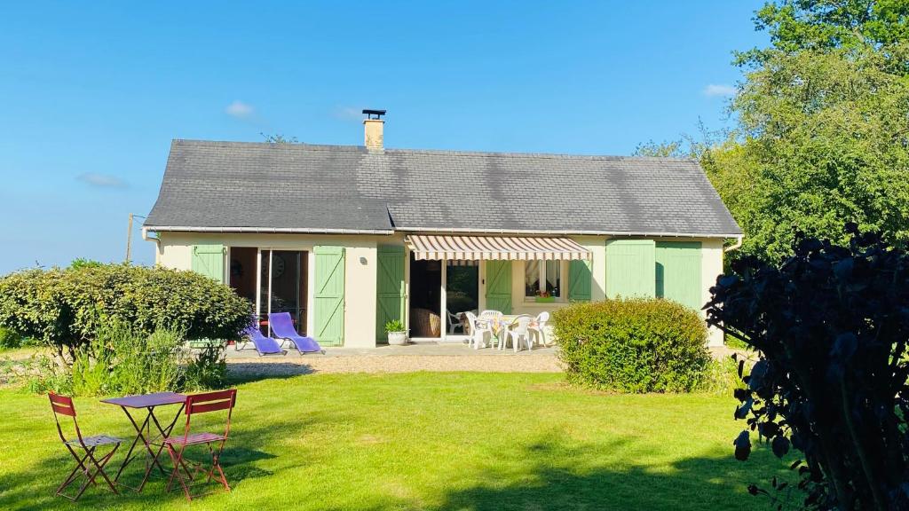 une maison verte avec une table et des chaises dans une cour dans l'établissement Le tulipier, à Manneville-la-Raoult