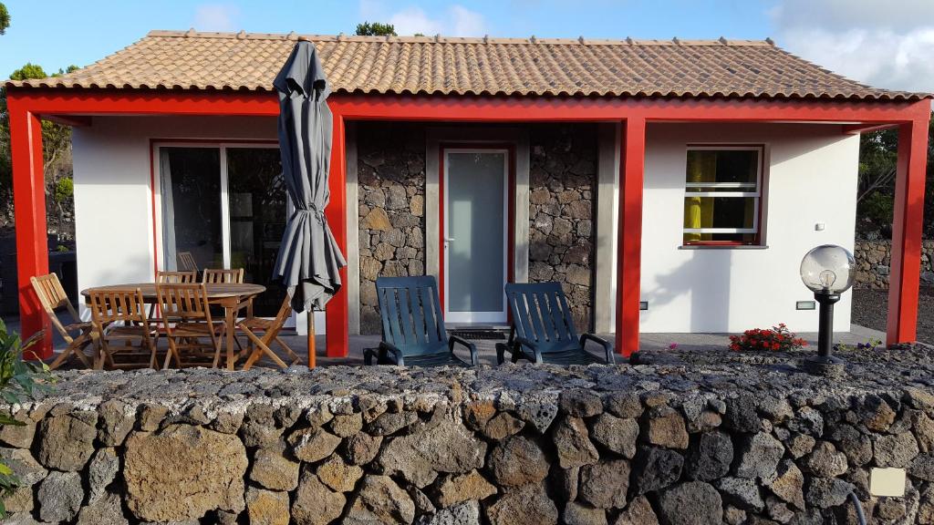 a cottage with a table and chairs and an umbrella at Casa da estrela sirius in Cabeço Chão