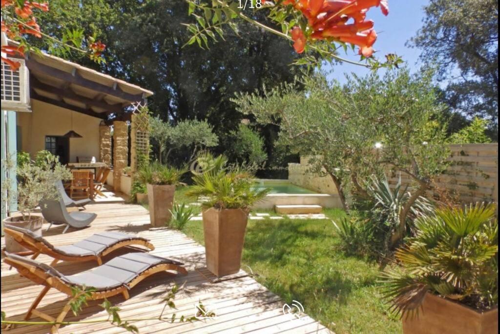 un jardín con terraza de madera con bancos y plantas en Chez Lydia - Rivière, Pont-du-Gard accès à pied !, en Castillon-du-Gard