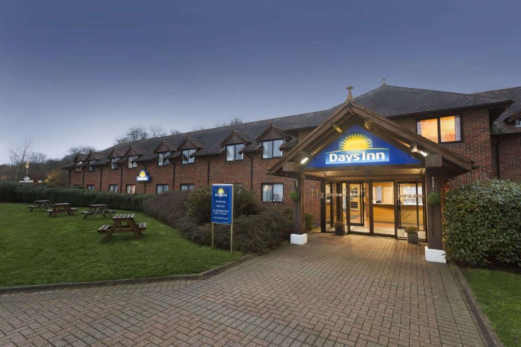 un bâtiment avec un panneau indiquant une auberge pour chiens dans l'établissement Days Inn by Wyndham Sevenoaks Clacket Lane, à Westerham