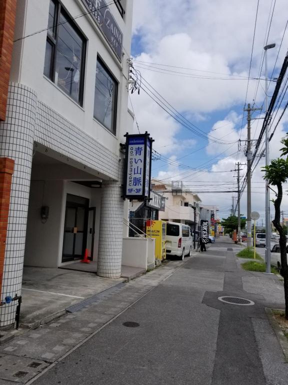 un edificio con un letrero al lado de una calle en Aoi sanmyaku en Awase