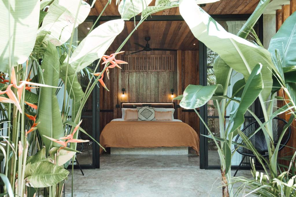 ein Schlafzimmer mit einem Bett in einem Zimmer mit Pflanzen in der Unterkunft Surfing Temple Hotel Boutique in General Luna