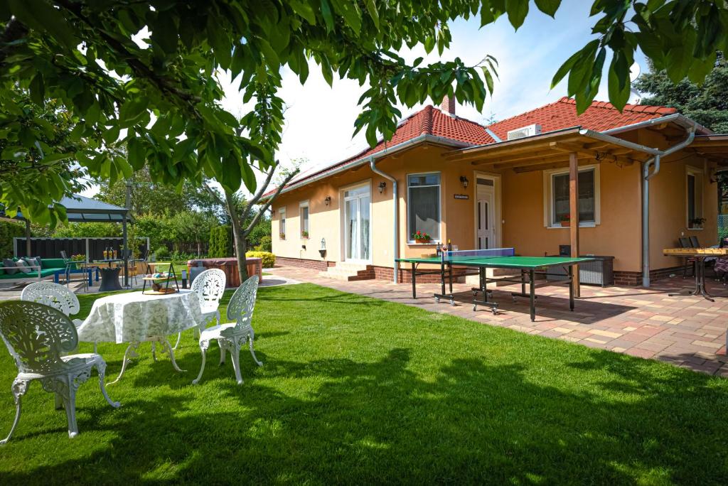 a yard with a ping pong table and chairs at Sunny Garden Pihenőház in Siófok