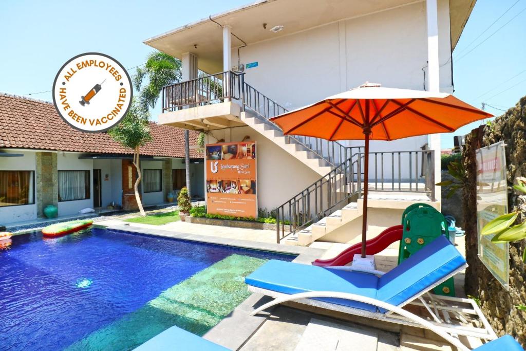 a pool with a chair and an umbrella next to a building at Lembayung Sari Homestay in Denpasar