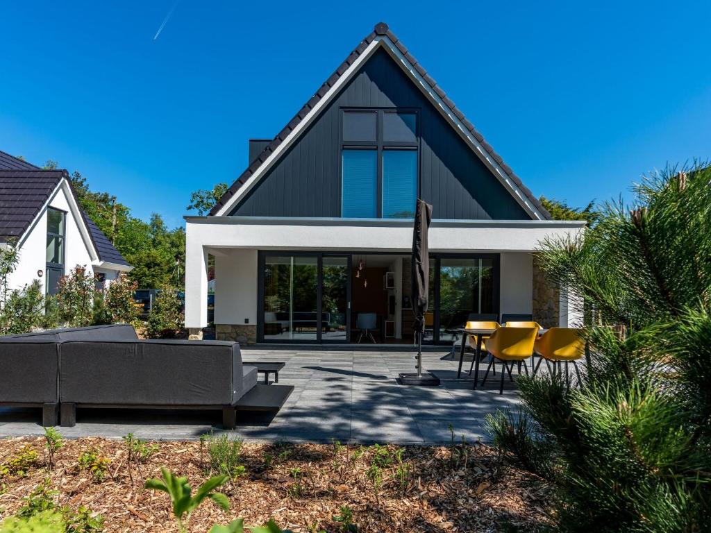 a house with a patio with yellow chairs and a couch at Energy neutral villa with wellness area in Den Burg