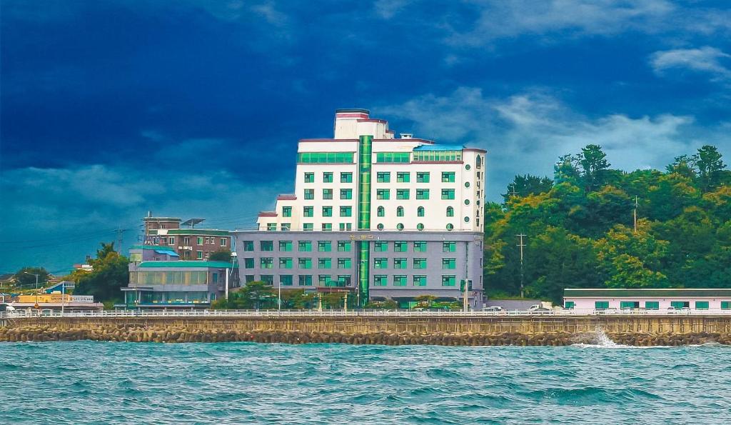 un gran edificio blanco junto a una masa de agua en Benikea Hotel Mountain & Ocean Daepohang, en Sokcho