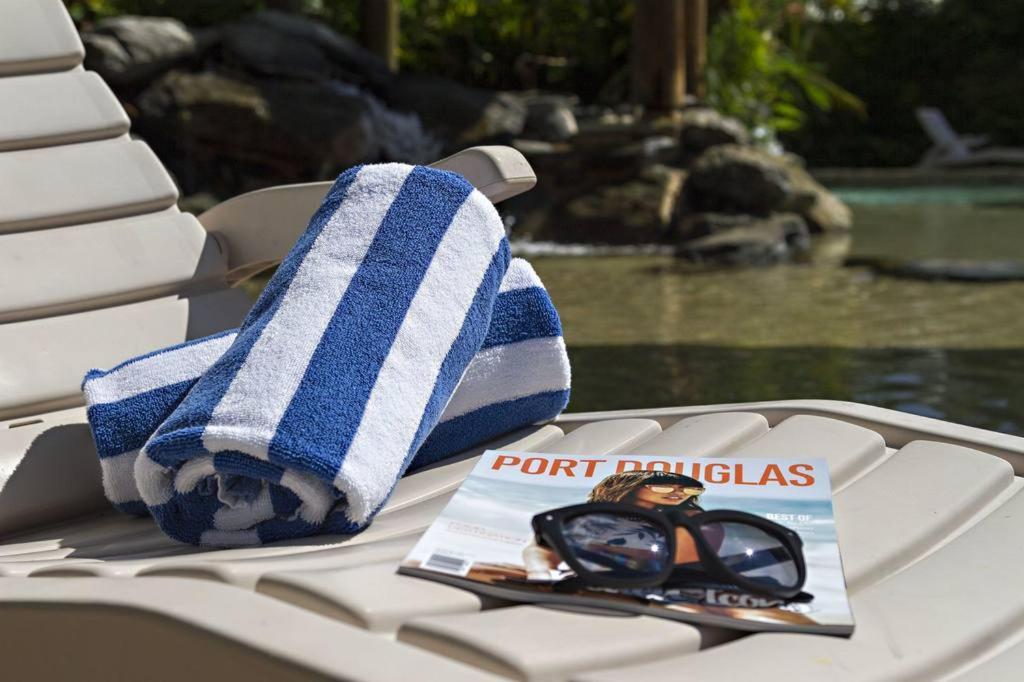 una toalla y un par de gafas de sol y una revista sobre una mesa en Port Douglas Plantation Resort en Port Douglas