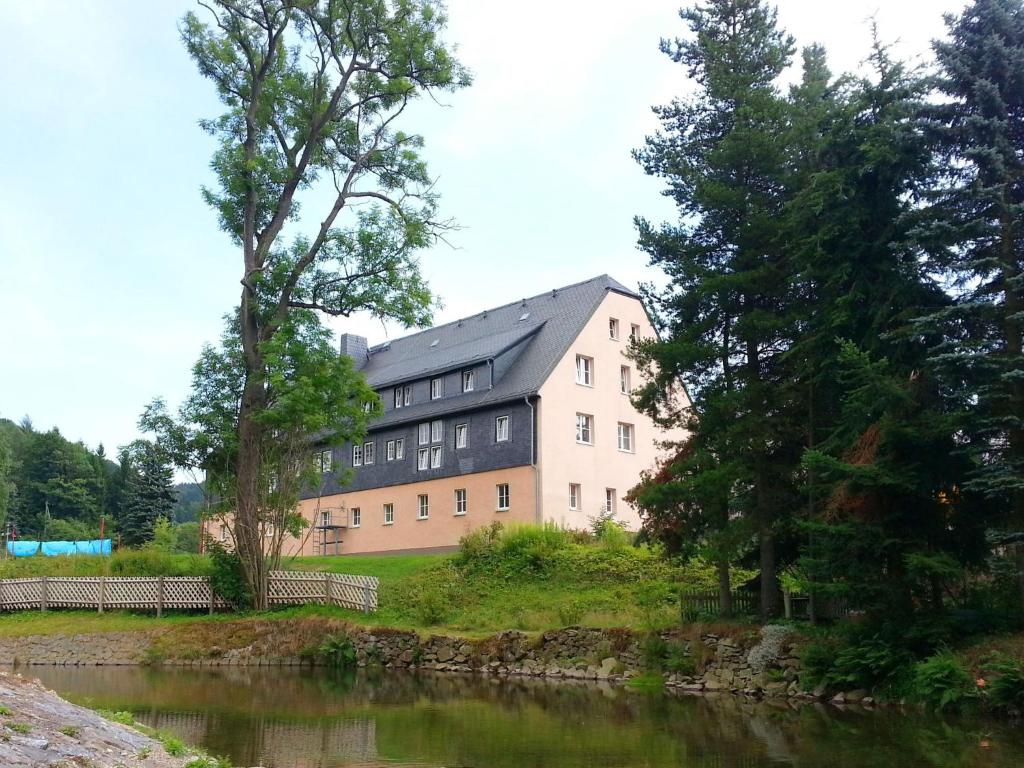 ノイウハウゼンにあるFlat near the ski resort in Rauschenbachの川の横の丘の上の建物