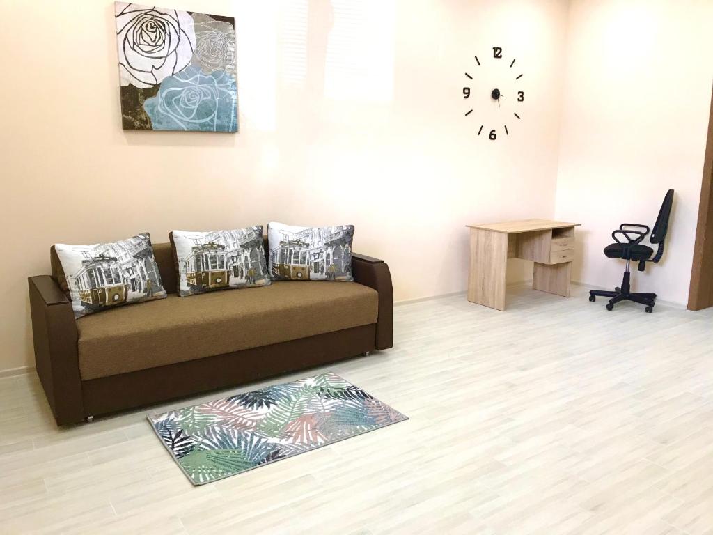 a living room with a couch and a clock on the wall at Комфортные апартаменты Smart in Khmelëva
