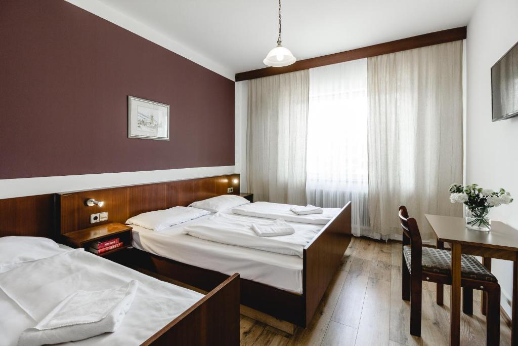 ein Hotelzimmer mit 2 Betten und einem Tisch in der Unterkunft Hotel Hoffinger in Wien