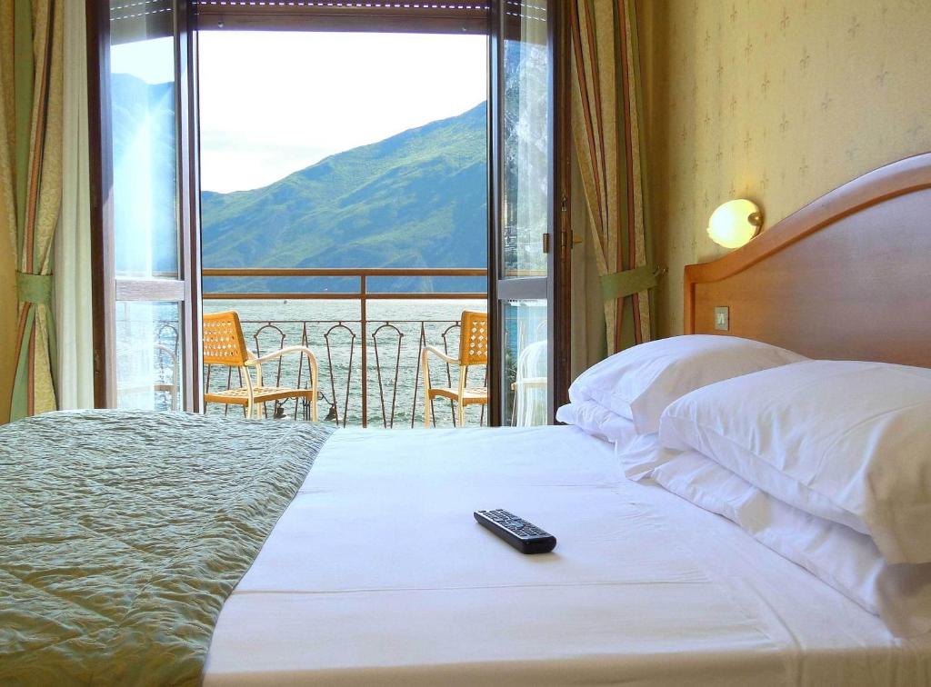 a bedroom with a bed with a remote control on it at Hotel Sole - Limone in Limone sul Garda