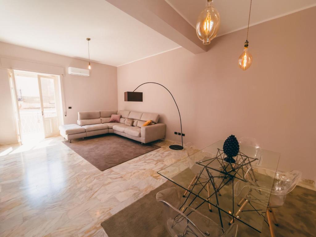 ein Wohnzimmer mit einem Sofa und einem Glastisch in der Unterkunft FICU PALACE in Syrakus