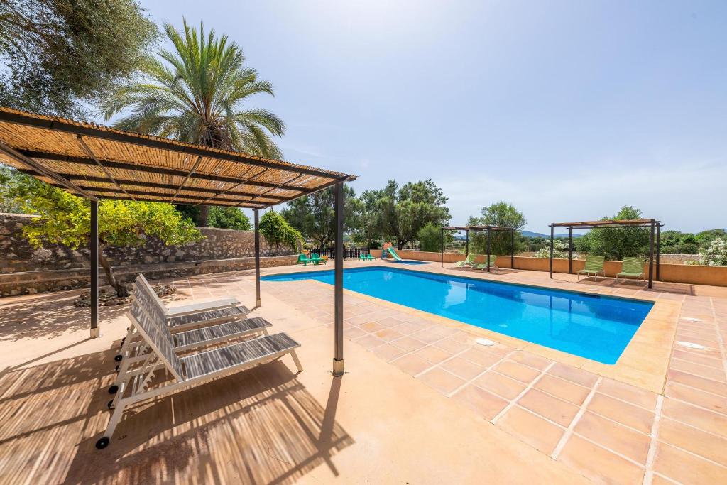 a swimming pool with a bench and a umbrella at Es Rafalet - Es Porxet in Manacor