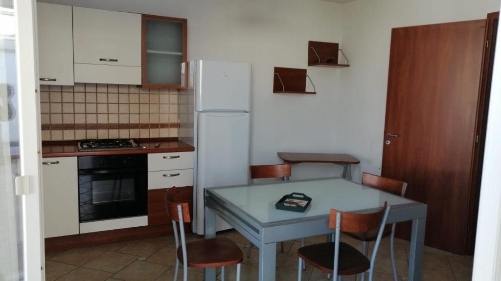 una cucina con tavolo, sedie e frigorifero di SPELU - Appartamento con terrazza fronte mare a Lido Marini