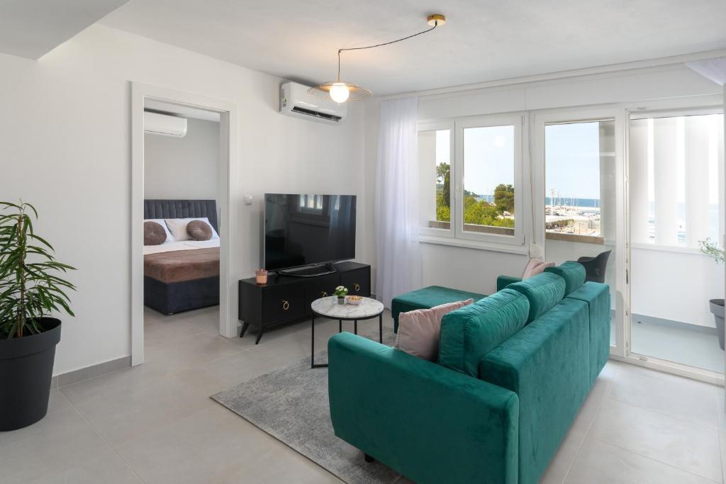 ein Wohnzimmer mit einem grünen Sofa und ein Schlafzimmer in der Unterkunft Ampelea apartment in Rovinj