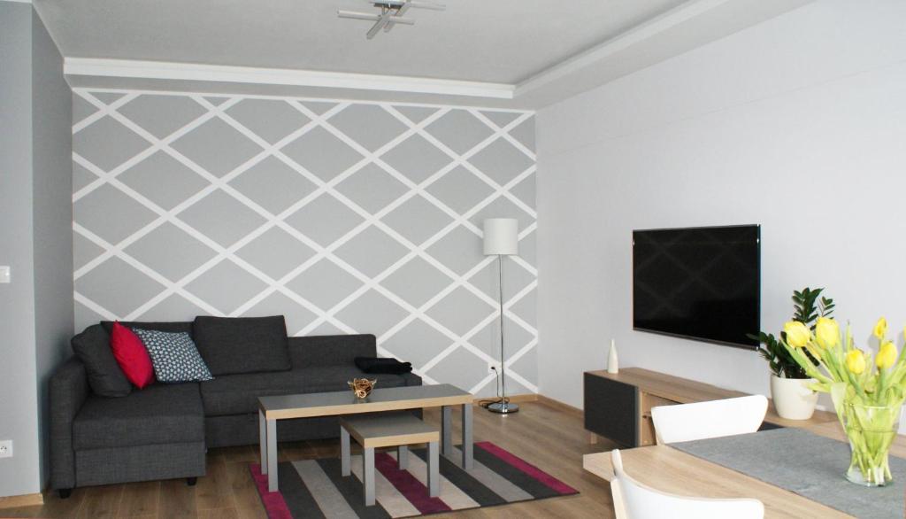 a living room with a couch and a tv at Apartament Imagus Oliwa in Gdańsk