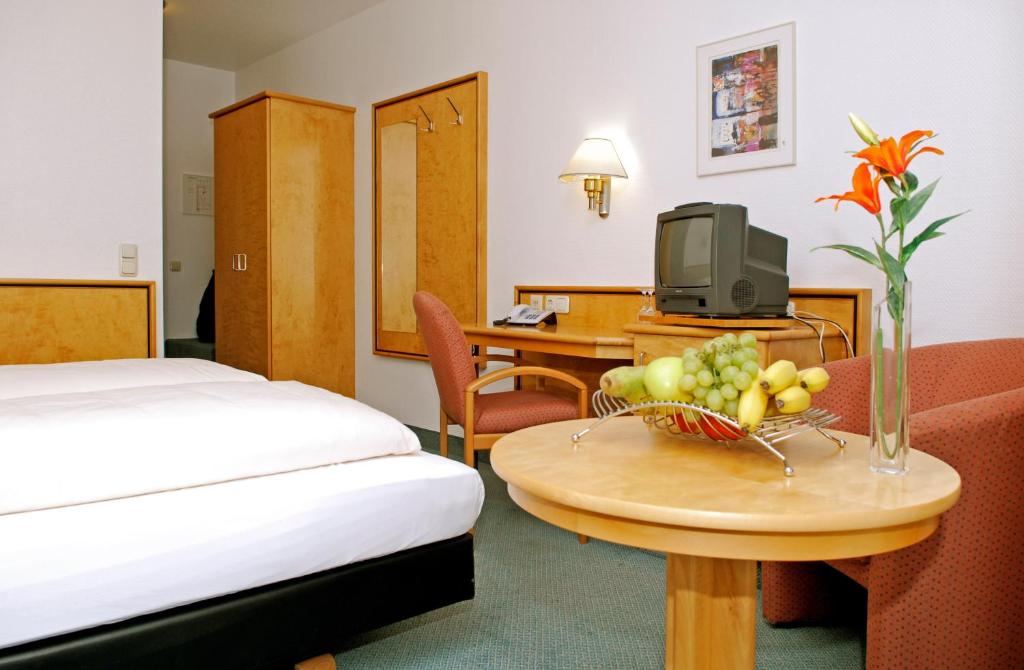 a hotel room with a bed and a table with a bowl of fruit at Matchpoint Hotel in Altdorf bei Nuernberg