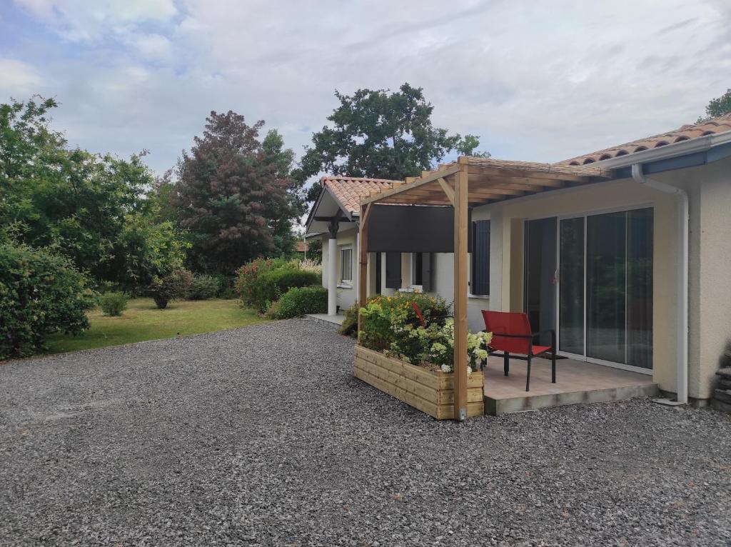 a house with a porch with a red chair on a gravel driveway at appartement Anna in Parentis-en-Born