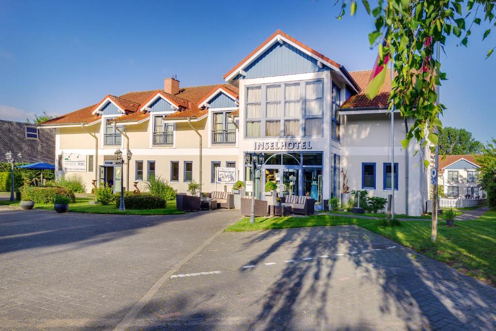 ein großes weißes Gebäude an der Straßenseite in der Unterkunft Inselhotel Poel in Gollwitz