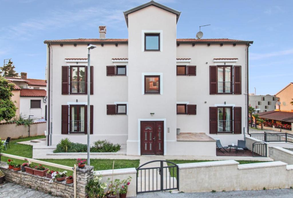 een wit huis met een hek ervoor bij Apartments Villa Alba II in Poreč