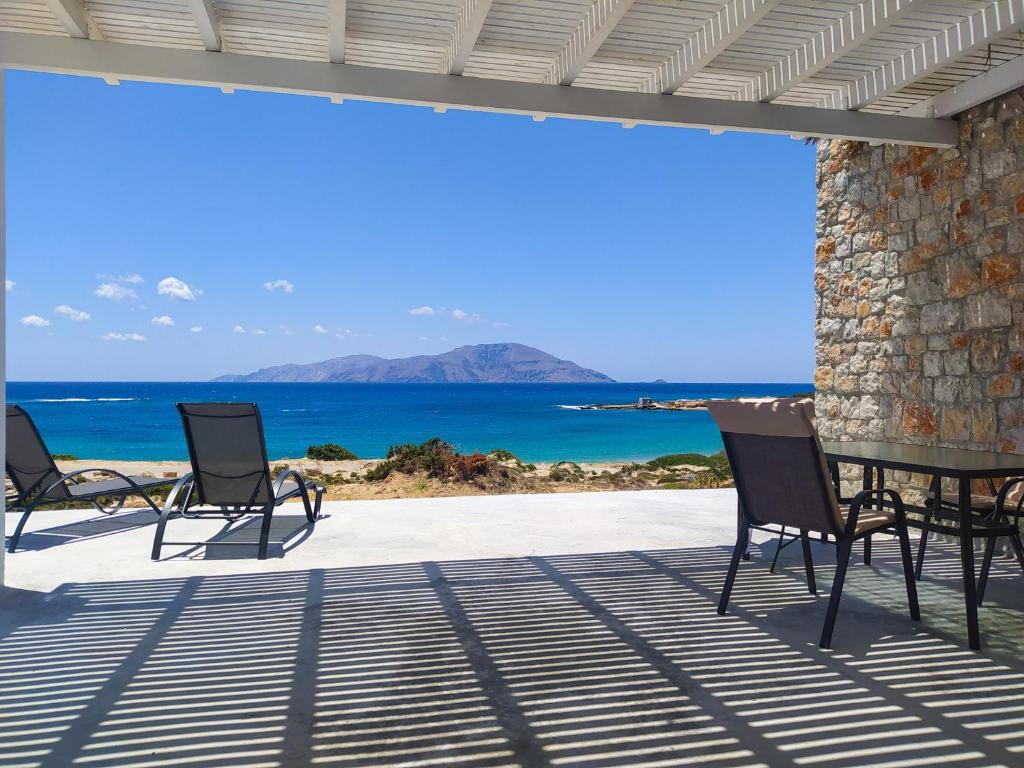2 krzesła i stół na patio z widokiem na ocean w obiekcie Kyanis Villa , Karpathos Afiartis w mieście Afiartis