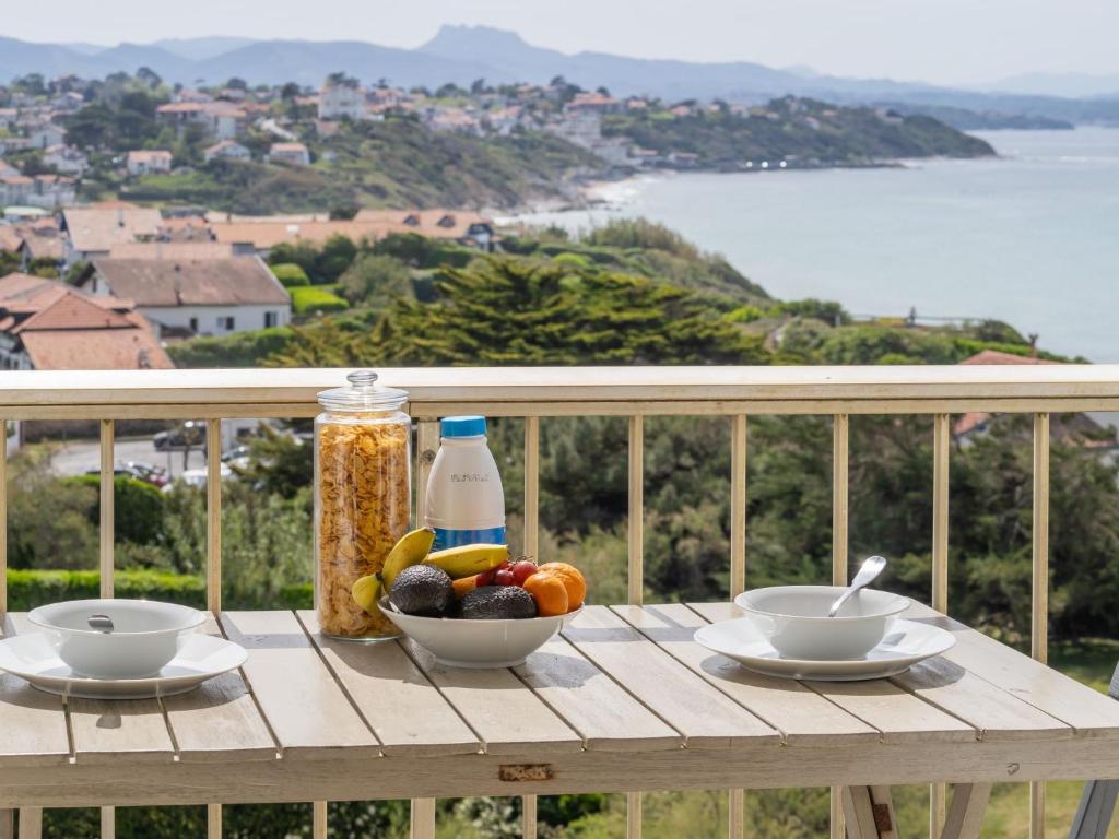 a wooden table with bowls of fruit and a bottle of milk at Apartment Ur Gaina-3 by Interhome in Bidart