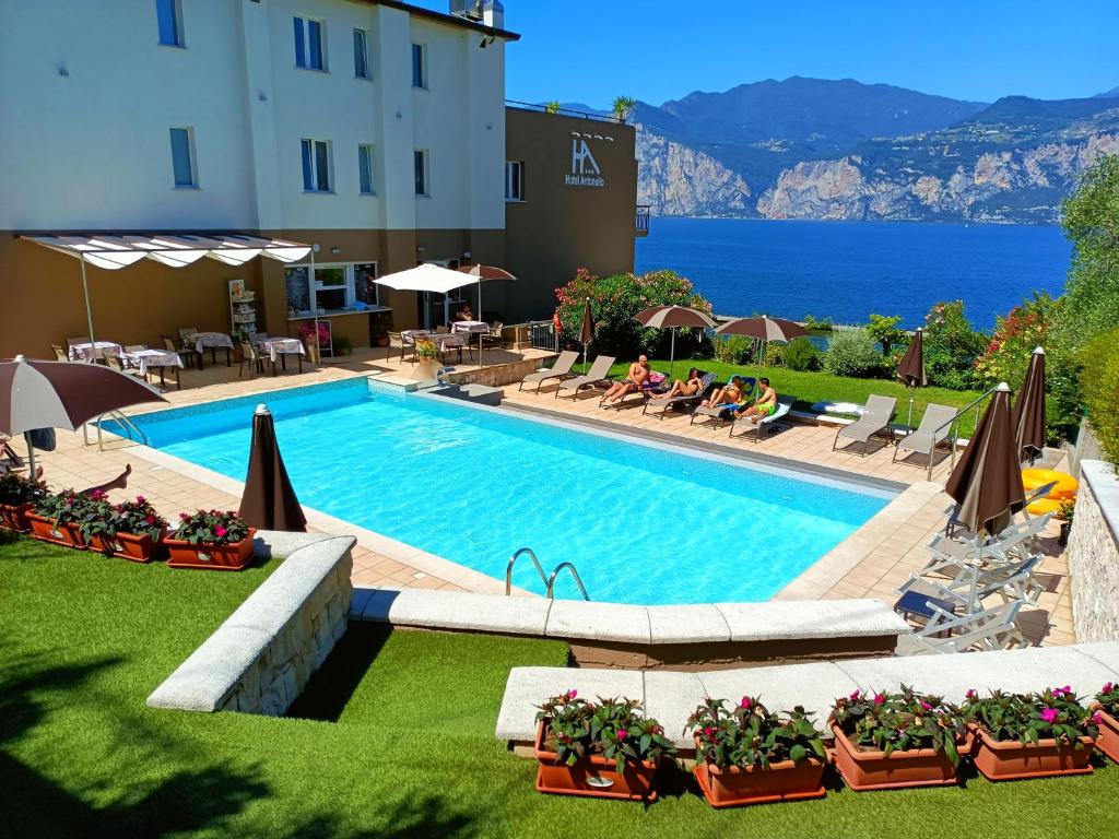 a large swimming pool with chairs and a building at Hotel Antonella in Malcesine
