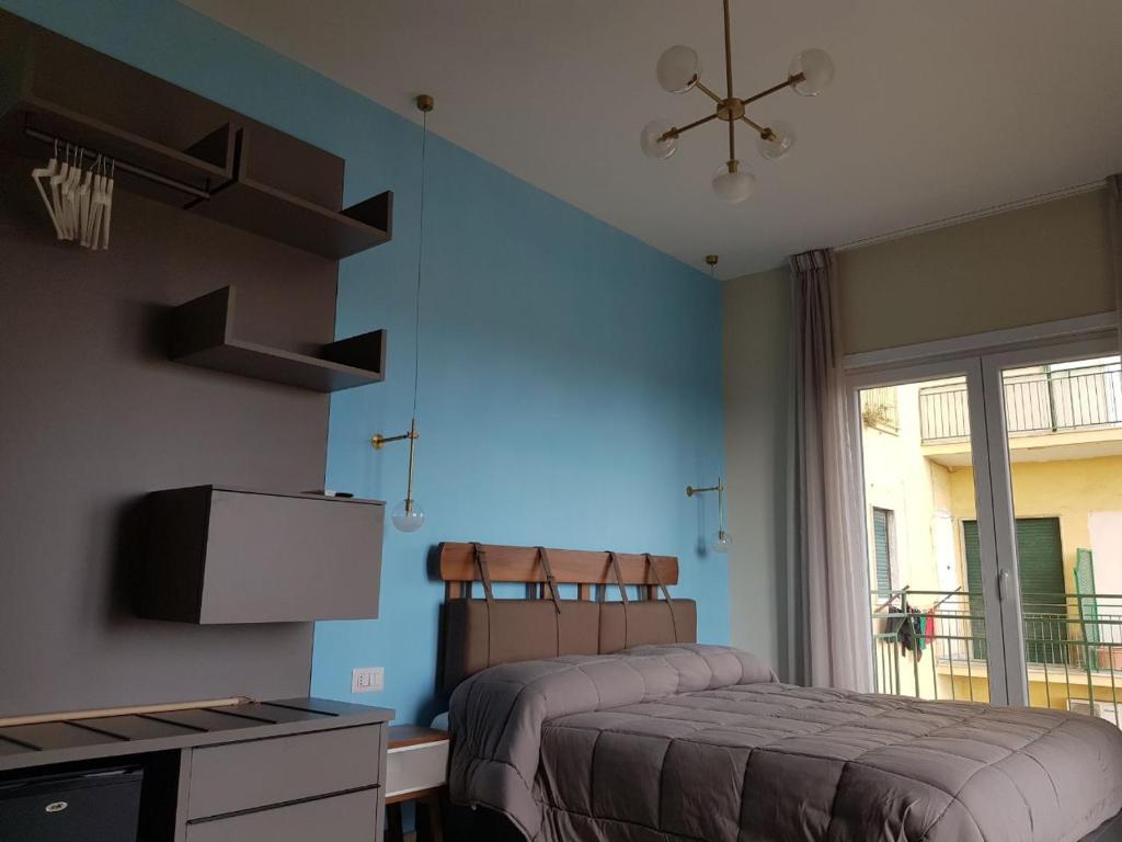 a bedroom with two beds and a blue wall at Euforia Napoli - Tre Sedi - Three Locations in Naples