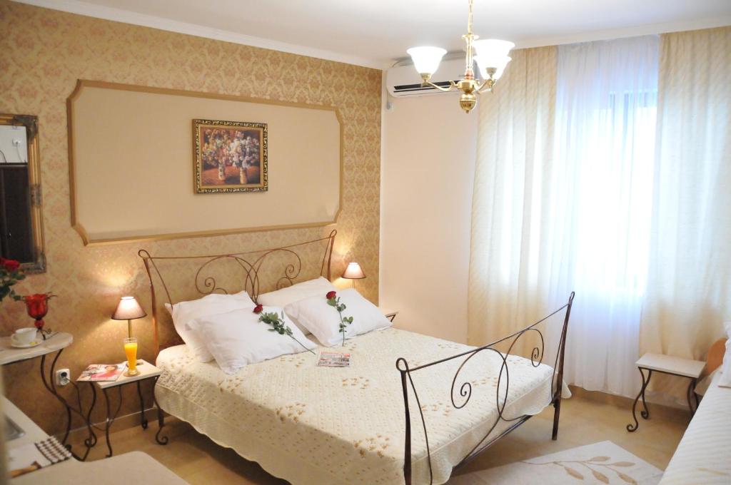 Schlafzimmer mit einem Bett mit weißer Bettwäsche und einem Fenster in der Unterkunft Royal Apartments in Niš